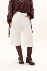 Bermuda de corte recto y tiro alto, confeccionada en gabardina blanca, con cierre frontal de botón y cremallera, y bolsillos laterales.