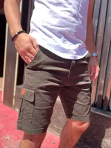 Bermuda cargo de gabardina en color azul marino, con bolsillos laterales con solapa y detalle de etiqueta de cuero sintético.