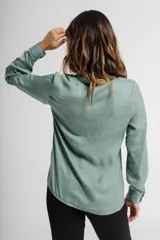 Camisa verde con cuello mao, de manga larga con puños abotonados y cierre frontal con botones.