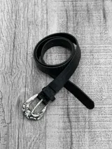 Cinto negro con hebilla plateada de metal con diseño irregular.