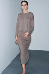 Falda midi de tiro medio confeccionada en tejido soft, con cintura elástica y abertura en la parte posterior.