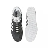 Championes adidas Gazelle de gamuza gris, con las icónicas tres bandas laterales en blanco, suela de goma blanca y detalle del nombre del modelo en dorado.