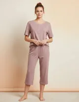 Pijama capri Lumiere de color rosado melange, compuesto por una remera de manga corta con escote redondo, cierre parcial de botones y un pequeño bolsillo en el pecho, y un pantalón capri con cintura elástica.