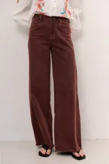 Jean de corte wide leg y tiro medio, con diseño de perneras amplias y terminación desmechada en el bajo.