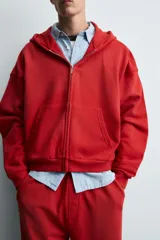 Sudadera roja con capucha, cierre frontal con cremallera, bolsillos tipo canguro y corte relaxed boxy fit.