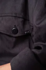 Camisa de estilo sobrecamisa en color beige, confeccionada en tela tipo gamuza o cuero sintético. Presenta cuello clásico, cierre frontal con botones, bolsillos delanteros con solapa y mangas largas con puños abotonados.