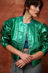 Campera de cuero con silueta oversize y corte levemente corto. Presenta cierre frontal metálico, cuello a la base y mangas amplias con detalles trenzados y recortes que aportan textura.