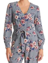 Enterito de crepe con estampado floral, escote en V, mangas largas con puños abotonados y lazo de ajuste en la cintura.
