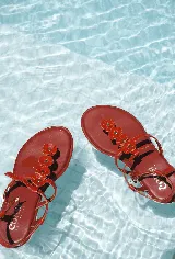 Sandalias bajas color hueso, con tira delantera con apliques de flores blancas y tira trasera con hebilla.