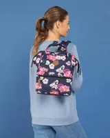 Mochila Cabaia modelo Adventurer, con diseño estampado de flores sobre fondo azul marino. Cuenta con doble asa superior, bolsillo frontal con cierre y detalles en cuero sintético.