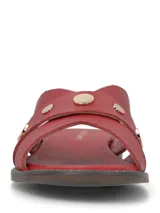 Sandalias planas de cuero rojo con tiras cruzadas y tachas metálicas doradas.