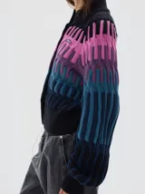 Cardigan de punto con diseño en degradé de colores, desde el negro en el cuello hasta tonos fucsia, violeta y azul. Presenta cierre frontal con botones, cuello redondo y mangas largas con volumen.