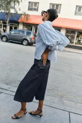 Camisa de cuello solapa y manga larga con puños abotonados. Presenta un diseño de rayas verticales azules y blancas con un estampado floral lineal superpuesto. Cierre frontal con botones.