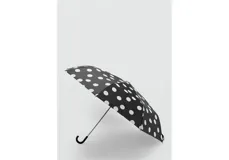 Paraguas plegable de color negro con estampado de lunares blancos grandes, cuenta con mango curvo ergonómico.