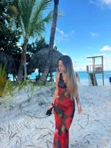 Vestido midi de microtul rojo con estampado de rosas y hojas verdes, escote en V con encaje negro y breteles finos regulables en la espalda.