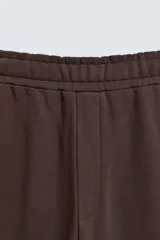 Pantalón jogger de corte relajado y pernera ancha, confeccionado en tejido de algodón con interior perchado. Cuenta con cintura elástica ajustable mediante cordón interior, bolsillos laterales y un bolsillo trasero de plastrón.