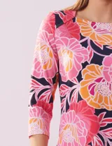 Remera de algodón estampada con flores en tonos celeste, azul y verde, sobre fondo negro. Tiene mangas 3/4 y escote cuadrado.
