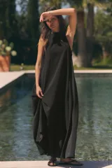 Vestido midi de corte fluido y diseño minimalista, con cuello redondo y mangas sisa. Presenta un cierre en la espalda con abertura y lazada ajustable.