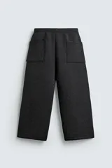 Pantalón de corte wide fit confeccionado en tejido técnico con efecto neopreno. Presenta cintura elástica ajustable con cordón, perneras anchas con costura frontal, bolsillos laterales y bolsillos traseros de plastrón.