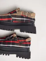 Mocasines con plataforma de goma negra, confeccionados en lona con estampa a cuadros en tonos violeta, amarillo y beige, y detalle de elásticos laterales ocultos.