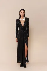 Vestido largo de lentejuelas color negro, con diseño cruzado y escote profundo en V. Presenta mangas largas, detalle fruncido en la cintura y un tajo lateral pronunciado.
