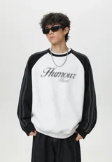 Buzo oversize de corte holgado, color gris melange en el cuerpo con mangas raglán en contraste color negro. Presenta cuello redondo, puños y cintura elastizados, costuras blancas decorativas a lo largo de las mangas y un estampado frontal con la palabra 'Humour' de efecto esfumado.