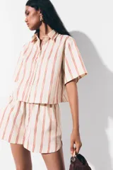 Short de popelina de algodón de tiro alto con cintura fruncida y bolsillos laterales discretos, de bajo levemente redondeado. Presenta un diseño de rayas verticales sobre base beige.