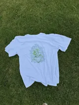 Remera color arena de manga corta con estampa en la espalda de un jarrón con flores.