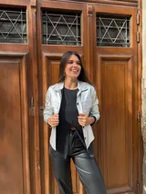 Chaqueta dorada metalizada con cuello camisero, cierre frontal con botones y bolsillos de parche en el pecho.