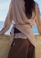 Blusa de lyocell y viscosa con estampado de rayas finas, cuello redondo, manga larga abotonada y detalle cruzado en la cintura.