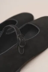 Zapato plano estilo Mary Jane de cuero negro, con punta fina y tira ajustable con hebilla sobre el empeine.