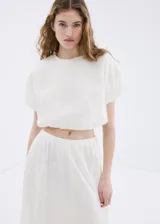 Falda midi evasé de color blanco, confeccionada en algodón con detalles bordados tonales, cintura elástica y forro interior.