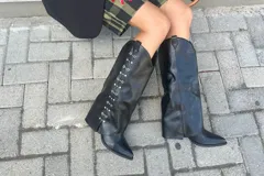 Botas de caña alta negras con punta en pico, taco bajo y detalles metálicos plateados en los laterales de la caña.