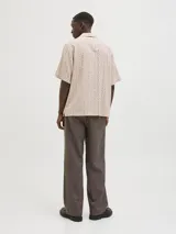 Camisa de manga corta Jack & Jones con cuello resort y cierre de botones. Diseño con estampado geométrico en tonos beige y marrón.