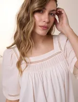 Blusa de corte holgado color marfil, confeccionada en mezcla de modal y algodón, con escote cuadrado y mangas cortas adornadas con detalles de puntilla calada.