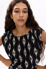 Vestido mini negro sin mangas, con estampado geométrico en tonos blancos, escote redondo fruncido, cintura drapeada y falda escalonada con volados.