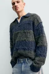 Polo de punto con textura, diseño de rayas horizontales en tonos gris y azul, cuello solapa con cierre frontal de botones y mangas largas con terminaciones en rib.