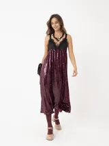 Vestido largo de lentejuelas color borgoña con detalles de encaje negro en el escote y tirantes finos.