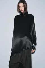 Blusa de Zara Woman Collection confeccionada en viscosa, con cuello alto, manga larga y diseño asimétrico en el bajo. Presenta un acabado satinado y cierre en la espalda.