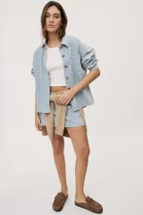 Falda corta de jean con diseño a rayas verticales celestes y blancas. Presenta tiro medio, bolsillos delanteros, pasadores en la cintura y cierre frontal con botón metálico.