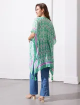 Kimono tejido con estampado abstracto en tonos azules, blancos y violetas. Tiene terminación de ruedo con borlas.
