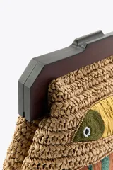 Bolso de mano tipo clutch confeccionado en rafia color beige con asa de madera oscura y cierre a presión. Decorado con dos peces bordados con cuentas y rafia de colores amarillo, marrón y verde.