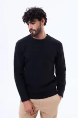 Buzo de tejido de punto color negro, con cuello redondo a la base y mangas largas. Presenta un diseño liso con textura acanalada.