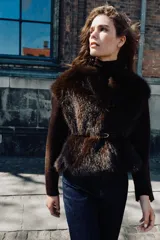 Chaqueta de punto gris con frente de piel sintética, cuello redondo, manga larga y cinturón fino efecto piel incorporado en la cintura. Cuenta con cierre frontal mediante ganchos metálicos y forro interior.
