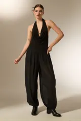 Pantalón tipo babucha de color negro, confeccionado en tela semitransparente con textura de rayas verticales y pequeños detalles en relieve. Presenta una cintura elástica cómoda y un corte holgado que se ajusta ligeramente en los tobillos.