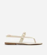 Sandalia plana color crema con tiras finas y apliques dorados en forma de conchas marinas.