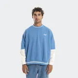Buzo crewneck de corte boxy y mangas murciélago, con diseño bicolor en azul y blanco. Presenta letras bordadas en el frente y detalles de líneas horizontales en cuello y ruedo.