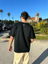 Remera negra de corte semi oversize con estampa frontal con la frase "Buena Vibra Est. 2022" en letras blancas.