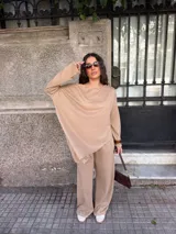 Conjunto gris melange compuesto por un buzo de cuello bote amplio y corte asimétrico con bolsillos, y un pantalón largo de corte recto y holgado.