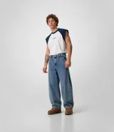 Pantalón de jean de corte balloon con volumen amplio en las piernas, cintura con pasacintos, bolsillos laterales y cierre frontal con botón y cremallera.
